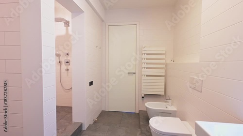 Modern bathroom with white subway tiles, gray floor tiles, white toilet, vanity, and towel rack, providing a clean, minimalist design.
