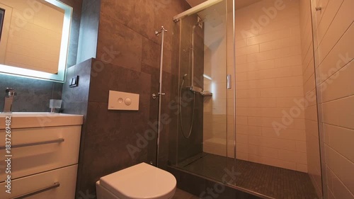 Stylish bathroom with modern vanity, mirror, toilet, and shower, featuring neutral tones and clean, minimalist design.
