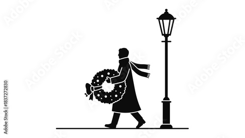 Silhouette of person carrying wreath walking past lamppost