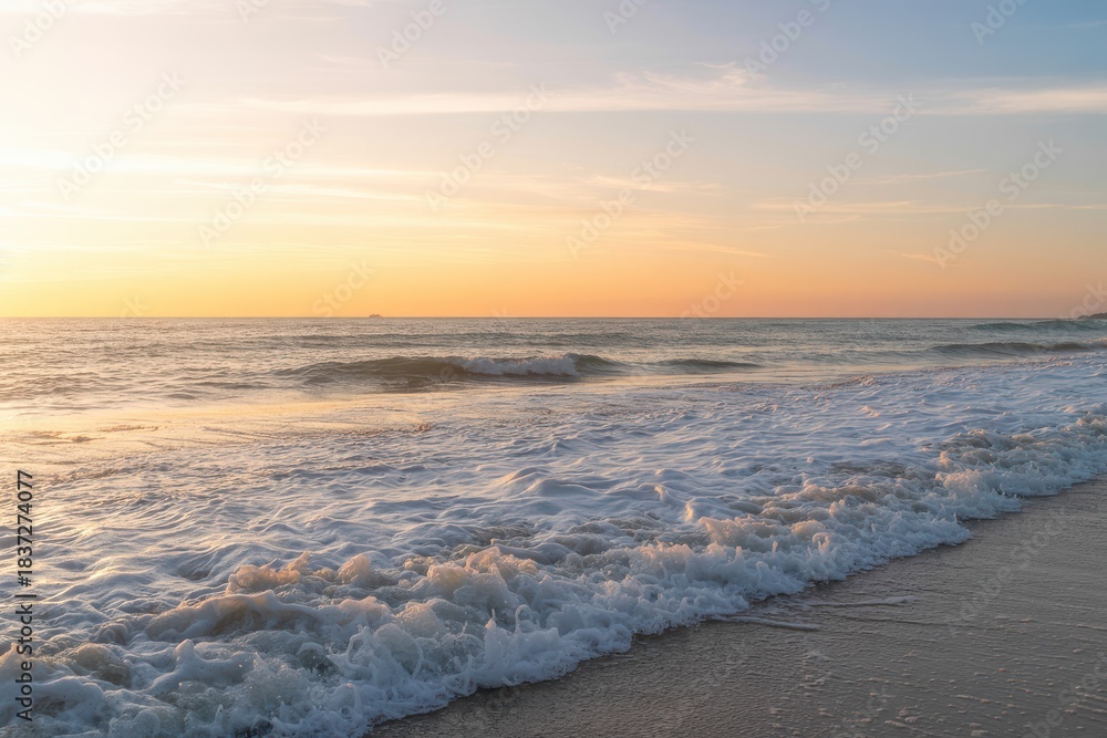 Obraz premium Stunning golden sunset illuminates foamy ocean waves rolling onto sandy beach