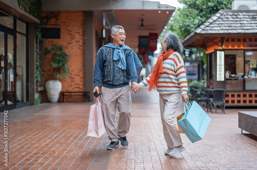 portrait bonding happy asian senior couple holding shopping bags,hands holding each other,walking together at the mall