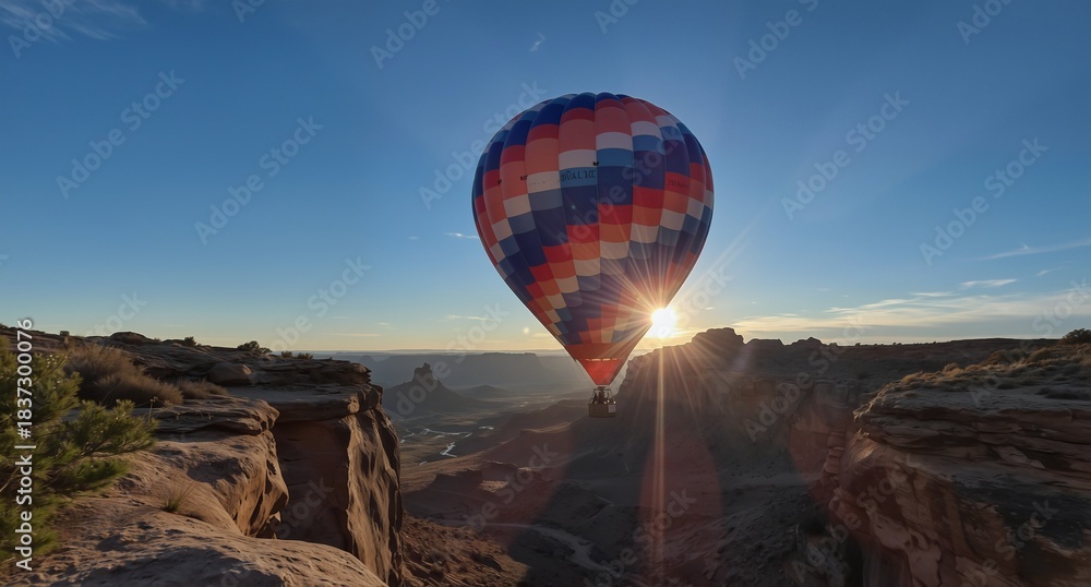 Obraz premium colorful hot air balloon soaring over canyonlands national park at sunrise with dramatic light rays.