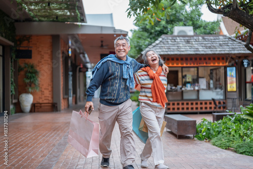 portrait bonding happy asian senior couple holding shopping bags,hands holding each other,walking together at the mall