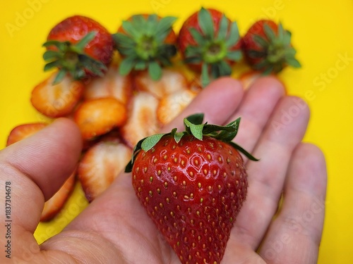 Delicious strawberry in hand and more on the background