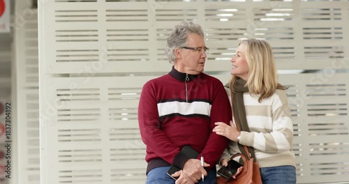 Pausing for ideas senior couple sitting on station bench jotting notebook as she holding smartphone