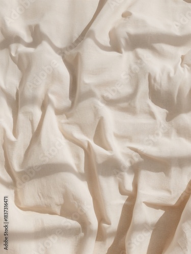 A light beige fabric with many natural wrinkles and folds. Strong sunlight creates deep shadows and a textured background.
