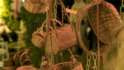 A collection of woven wicker bags and round baskets hangs from strings in a softly lit Christmas market stall display, evoking craft, handmade charm, and gift ideas for holiday season