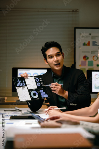 Business professional confidently presenting financial data charts on a tablet to colleagues, discussing market analysis and strategy
