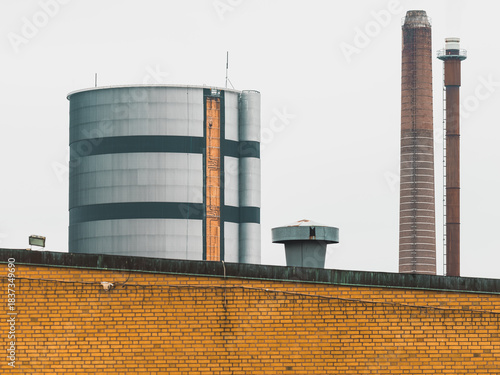Industrial buildings located in Boras, Sweden, showing a water tower and smokestack against a cloudy sky on a cool day