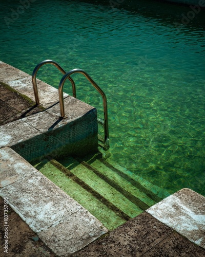 swimming pool with metal handrails and green water