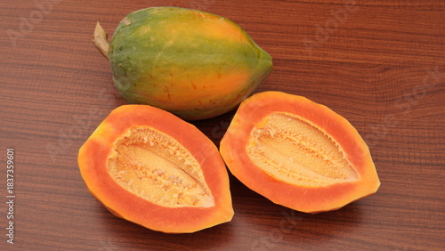 A whole papaya and slices on a wooden table. Tropical fruit.