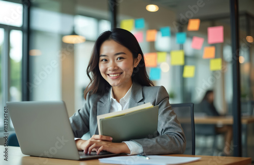 Happy Asian businesswoman working on laptop in bright modern office. Confident young female employee smiles sitting at desk holding documents. Successful pro manager plans project. Enjoys corporate Free Download Happy Asian businesswoman working on laptop in bright modern office. Confident young female employee smiles sitting at desk holding documents. Successful pro manager plans project. Enjoys corporate - GFXLoad