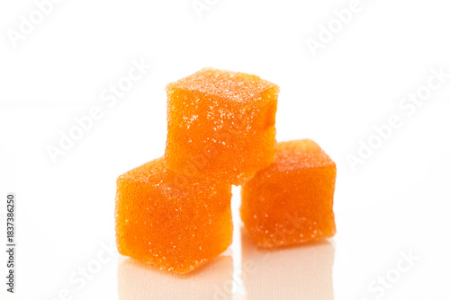Three orange cubes of marmalade candy on a white background