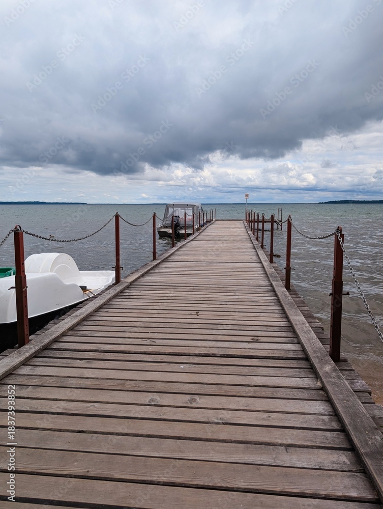 Fototapeta premium Naroch, Belarus, July 11, 2025. A large wooden pier on a lake before a thunderstorm in summer.