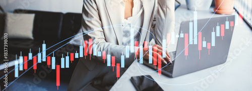 A smiling woman entrepreneur in glasses is engaged in her work at a laptop in a warm, cozy coworking space. She thoughtfully gazes out the window while completing her project.