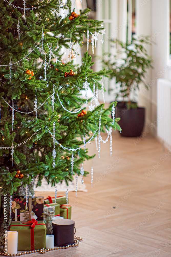 Fototapeta premium A cozy indoor scene featuring a festive Christmas tree adorned with sparkling decorations and gifts