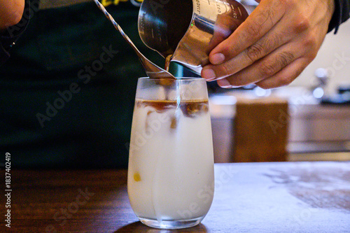 Barista preparing iced latte coffee drink with milk