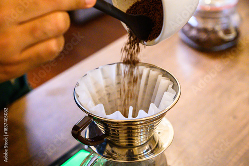 Hand pouring ground coffee into a pour over filter