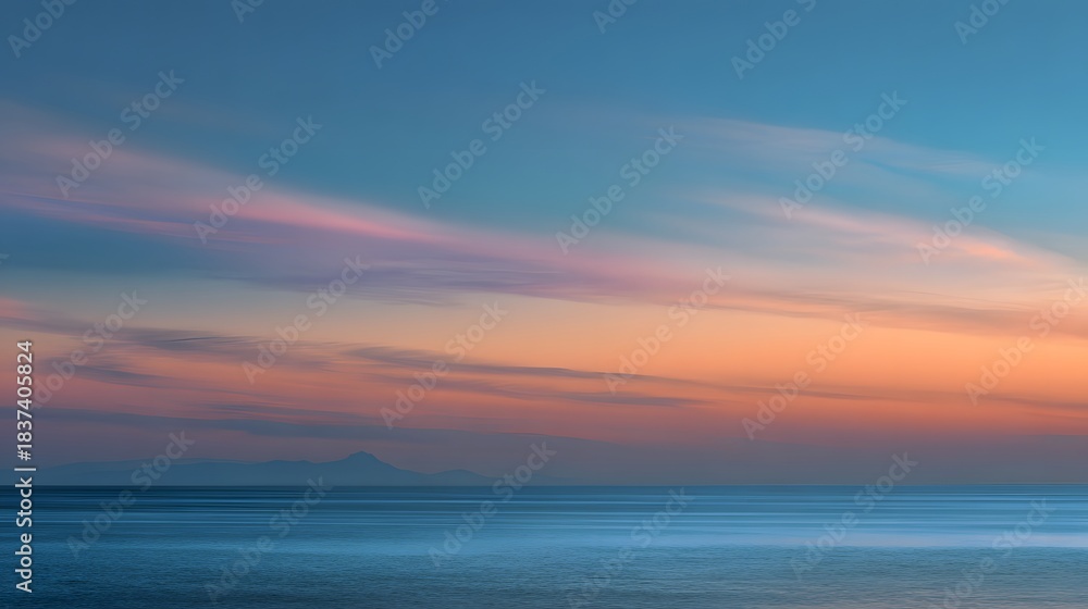 Obraz premium Serene ocean landscape features layered colorful clouds above distant coastal silhouette at twilight