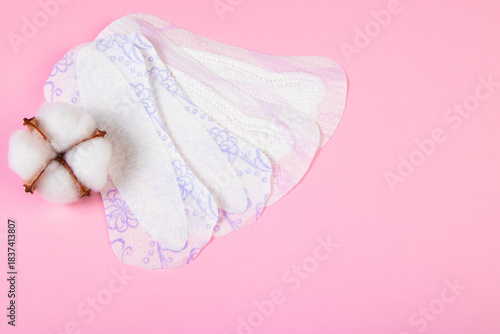 Sanitary pad and cotton flower on pink background. Daily feminine hygiene product. Menstruation and womens health concept. Copy space.