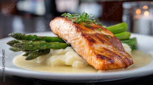 Medium-sized pan-seared blackened salmon served with tender asparagus and creamy mashed potatoes, presented in a smooth, velvety sauce on a elegantly styled plate.