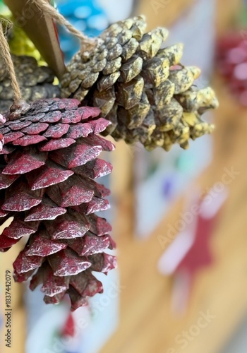 Close-up of a small bundle of pine cones with a blurred Christmas market background. Warm festive atmosphere, perfect for holiday designs, winter ads, and seasonal