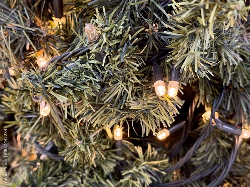 Close-up of a Christmas garland with warm glowing lights on an artificial tree, creating a cozy festive atmosphere. New year mood