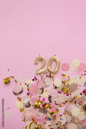 Golden candles in the shape of the number 20 on confetti background. Happy birthday vertical banner. Selective focus and copy space