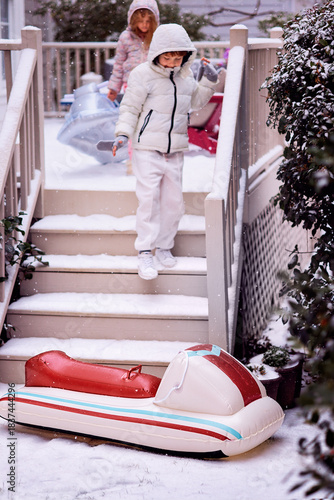 Inflatable Snow Sled Ready for Winter Fun - Children Approaching Their Sled on a Snowy Day. Winter Activity and Outdoor Play
