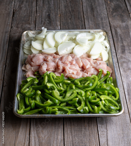 Sheet pan chicken fajitas with sliced onions, green bell peppers, and seasoned chicken arranged on a baking tray. Fresh, simple, and perfect for meal prep or easy dinner recipes.