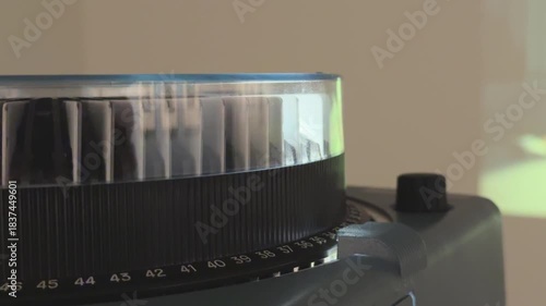 Vintage carousel slide projector running in a dark room with sound, rotating slide tray, warm light beam and changing photos creating a nostalgic analog presentation atmosphere.