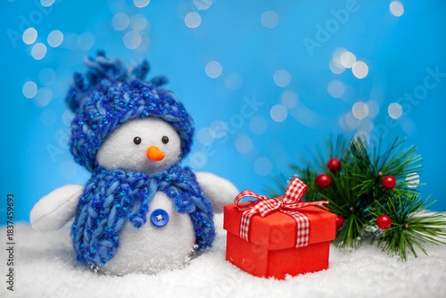 A Christmas or New Year's card. A funny snowman with a gift on a background of snow, winter and fir branches. handmade work.