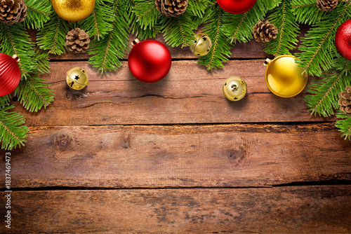 Christmas background with pine branches, jingle bells and colorful baubles on rustic wooden table, festive holiday border with copy space. High resolution.