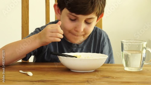 Boy eats noodles at the kitchen