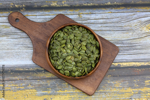 Pumpkin seeds in a wooden bowl on a wooden  background