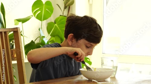 Boy eats noodles at the kitchen
