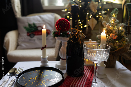 A festive bottle of champagne on the table with candles. Christmas atmosphere