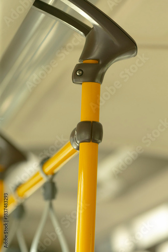 Closeup yellow bus pole with ergonomic grip, textured plastic and metal mounting visible, focused detail highlights maintenance and accessibility features, ideal for transit safety and equipment