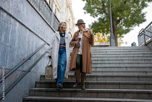 Two friends enjoy a lively conversation while walking down the staircase in a vibrant urban setting