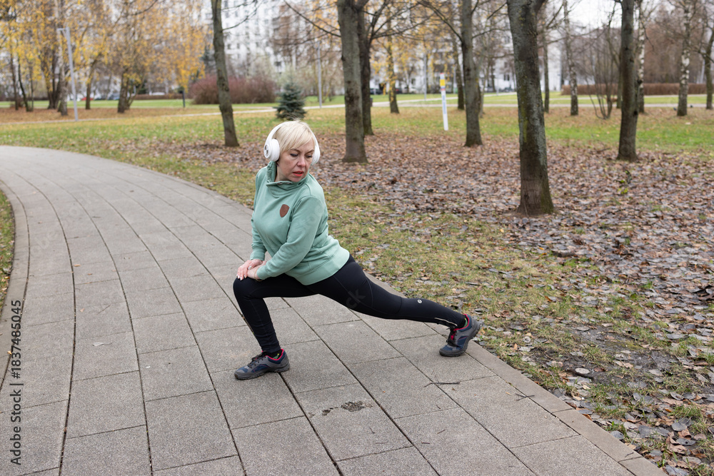 Fototapeta premium A woman with short blonde hair exercises in a park in nature. Sports and healthy lifestyle.