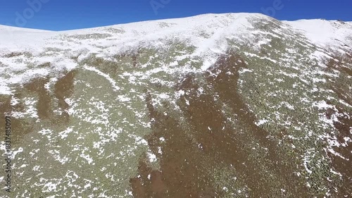 Aerial view of thin fresh winter snow on a treeless high altitude mountain ridge in Mongolia terrain. Sunny cloudless valleys of the Mongol lands show bright cold scenery across the highland landscape