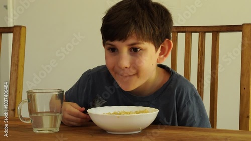 Boy eats noodles at the kitchen