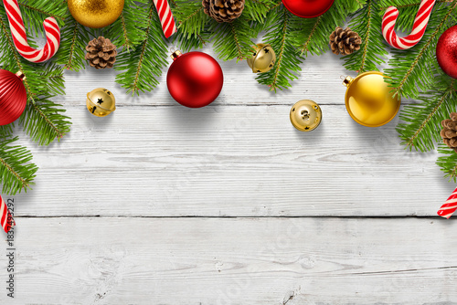  Christmas background with pine branches, jingle bells, candy cane and colorful baubles on rustic wooden table, festive holiday border with copy space. High resolution.