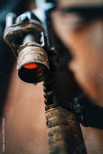camouflaged rifle with a collimator sight