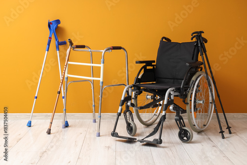 Bilde på lerret Medical walker with crutches and wheelchair near orange wall
