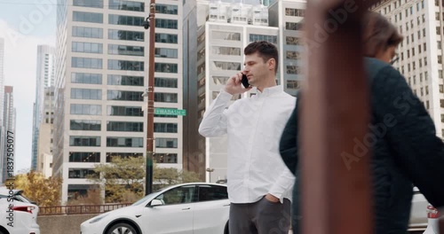 City street businessman making phone call, midday downtown with modern high-rise buildings and parked cars, man in white shirt using smartphone with focused