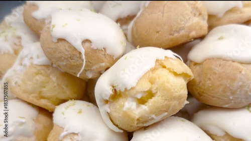 Several white chocolate Carolinas topped with lemon zest displayed in a Brazilian bakery showcase.