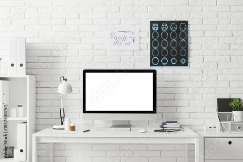 Blank computer monitor on desk near white brick wall in medical office