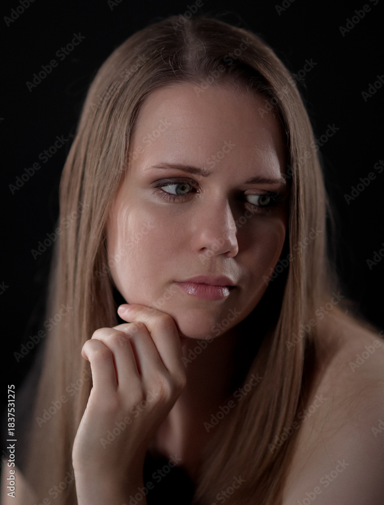 Obraz premium Studio portrait of a beautiful young woman with long blonde hair and green eyes against a black backdrop. This image is suitable for fashion beauty and lifestyle projects.