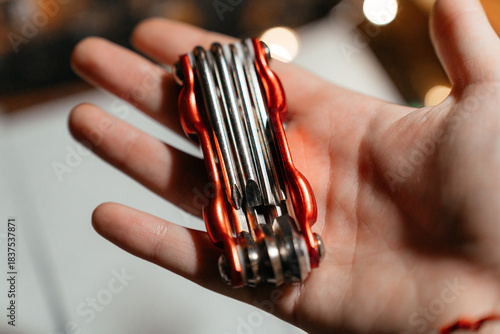 A compact red multitool resting in an open hand, showcasing its metal bits and practical design. Perfect for illustrating concepts of repair, craftsmanship, portability, and everyday utility.